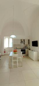 a white kitchen with a table and chairs in it at La Casetta 22 in Andrano