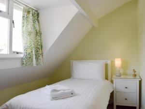 Schlafzimmer mit einem weißen Bett und einem Fenster in der Unterkunft Millies Cottage in Keswick