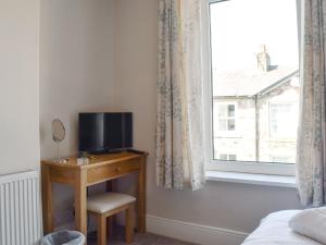 ein Schlafzimmer mit einem TV auf einem Schreibtisch neben einem Fenster in der Unterkunft Millies Cottage in Keswick