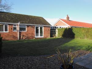 a brick house with a large lawn in front of it at Stileaway in Potter Heigham
