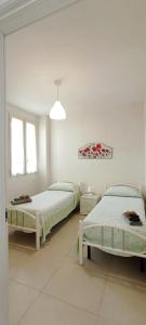 two beds in a room with white walls and windows at La Casetta 22 in Andrano