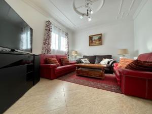 a living room with red couches and a flat screen tv at Magnifique villa - 5 chambres - Ifrane in Ifrane