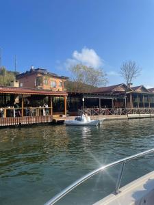 um pequeno barco na água ao lado de um restaurante em Ağva Kapım Otel em Şile
