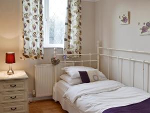 a bedroom with a bed and a window with curtains at The Glade in Ferring
