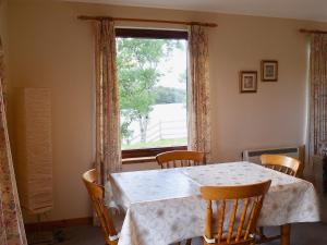 a dining room with a table and chairs and a window at The Narrows in Poolewe