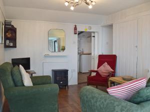 a living room with two green chairs and a fireplace at Log Cabin in Lamphey