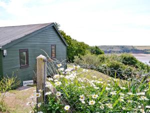 a green house with a fence and flowers at Log Cabin in Lamphey