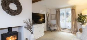 a living room with a television and a fireplace at BEECH COTTAGE in Hatherop