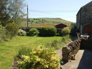 a garden with a stone wall next to a house at Gill Barn in Bampton