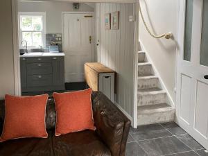 a living room with a leather couch and a staircase at Holme Crest in Staithes