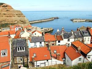 a group of buildings with red roofs and the ocean at Holme Crest in Staithes