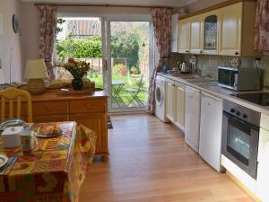 a kitchen with white appliances and a table in front of a window at The Warren in Bacton