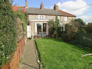 a small garden with a house with a lawn at The Warren in Bacton