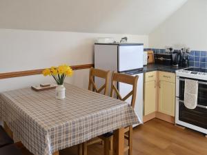 a kitchen with a table with yellow flowers on it at Fron Erch Cottages - 2711 in Llanarmon