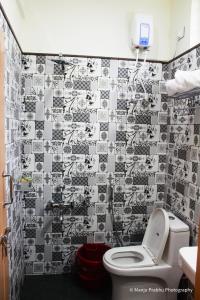 een badkamer met een toilet en een betegelde muur bij Kurinji Inn in Attigundi