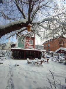 um quintal coberto de neve com mesas e cadeiras em frente a um edifício em Ağva Kapım Otel em Şile