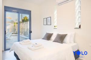 a white bedroom with a large bed with towels on it at Villa YOLO in Almirida