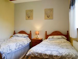 PentraethにあるBlack Horse Cottageのベッドルーム1室(ベッド2台、ナイトスタンドのランプ付)