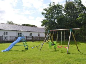 a playground with two swings and a slide at Black Horse Cottage in Pentraeth