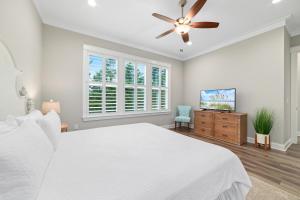 a bedroom with a white bed and a ceiling fan at Starfish Cottage in Gulf Shores +49 photos