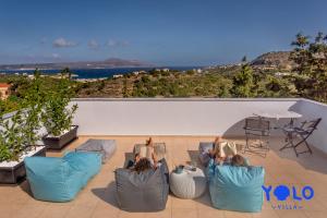 Dos personas sentadas sobre sillas en un patio con vistas al océano en Villa YOLO, en Almyrida