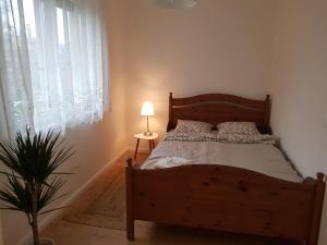 Dormitorio con cama de madera con lámpara y planta en Kislakás Esztergomban, en Esztergom