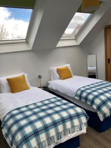 two beds in a room with two windows at Cosy 2 Bedroom Coach House in Belfast