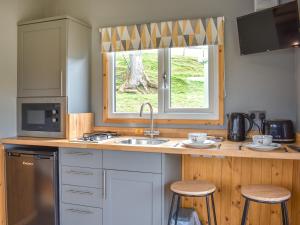 una cocina con fregadero y una ventana con taburetes en The Ash Uk38291 en Crosby Garrett