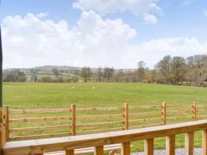 a wooden fence in front of a field with sheep at The Ash Uk38291 in Crosby Garrett