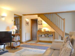 uma sala de estar com um sofá e uma escada em Wren Cottage em Goodrich