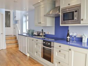 a kitchen with white cabinets and blue counter tops at Buckingham Cottage in Ventnor