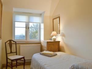 GoodrichにあるWren Cottageのベッドルーム1室(ベッド1台、椅子、窓付)