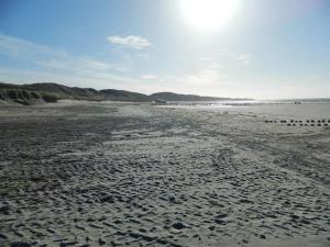 a sandy beach with the sun in the distance at Modern en sfeervol appartement aan zee met airco in Zoutelande