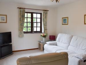 a living room with a white couch and a tv at The Berry - 15607 in Marldon