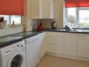 a kitchen with a washer and dryer in it at Rosehill in Goodrington