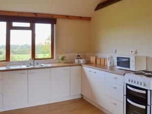 a kitchen with white cabinets and a sink and a window at The Old Calf House in Little Baddow