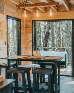 プコンにあるRUKAKUTRAL refugio de bosqueのテーブルと椅子、窓が備わる客室です。