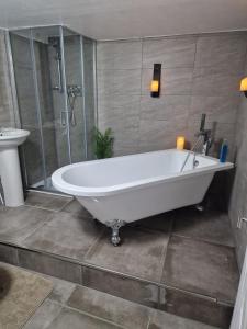 een badkamer met een wit bad en een douche bij Penbryn Holidays No 2 in Barmouth