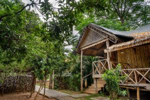 ein Holzhaus mit einem Strohdach und Bäumen in der Unterkunft Farm Stay Resort - Shamirpet, Hyderabad in Hyderabad