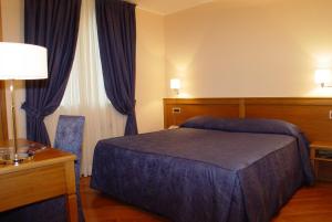 a hotel room with a bed and a desk and curtains at Hotel Iris in Genoa