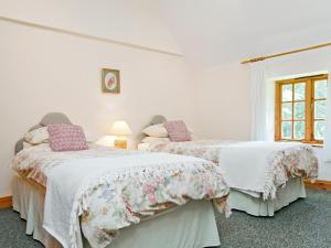 two beds in a bedroom with white walls and a window at Thatch Cottage in Saint Hilary