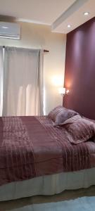 a bed in a bedroom with a purple wall at Chañar y Algarroba in Cafayate +7 photos