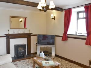 a living room with a fireplace and a tv at The Stables - 24971 in Frosterley