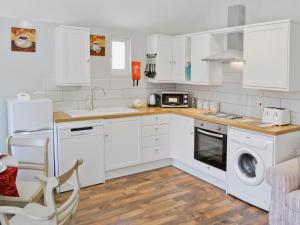 a kitchen with white cabinets and a washer and dryer at The Stables in Forncett Saint Mary