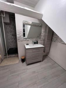 een badkamer met een wastafel en een spiegel bij Appartement Little Stuart in Dol-de-Bretagne