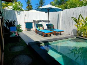 a patio with two chairs and an umbrella next to a pool at Little Lodge in Gili Trawangan