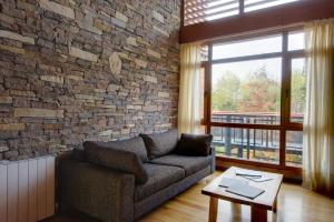 uma sala de estar com um sofá e uma parede de tijolos em Amonite Apart & Spa em San Martín de los Andes