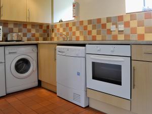 een keuken met een wasmachine en een wasmachine bij Honeysuckle Cottage - 29938 in Holcombe Burnell