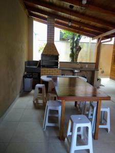 cocina con mesa, taburetes y parrilla en Casa praia bombinhas 150m mar, en Bombinhas