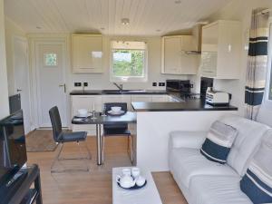 a living room with a white couch and a kitchen at The Cabin in Astley